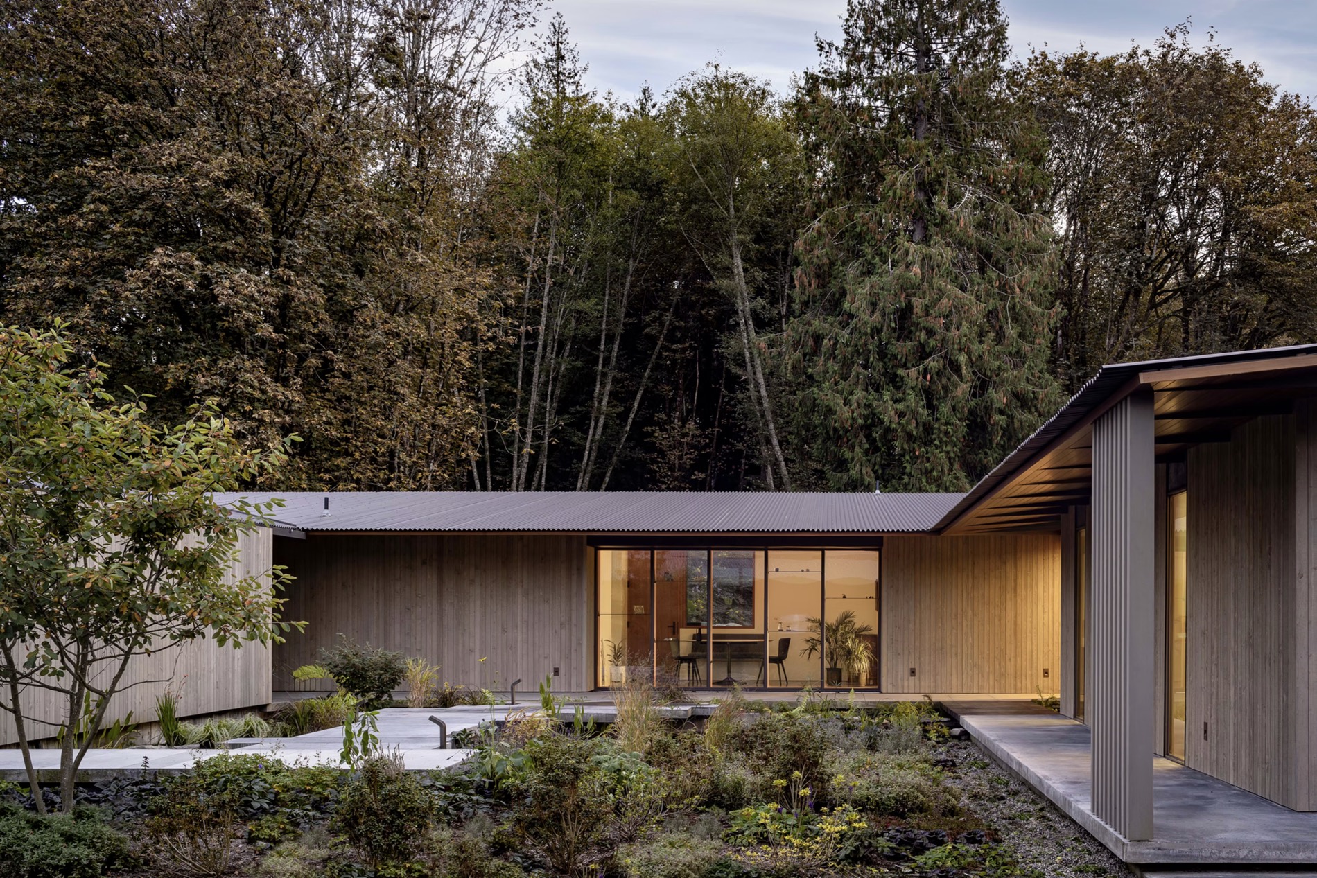 A timber house glowing at dusk in the forest