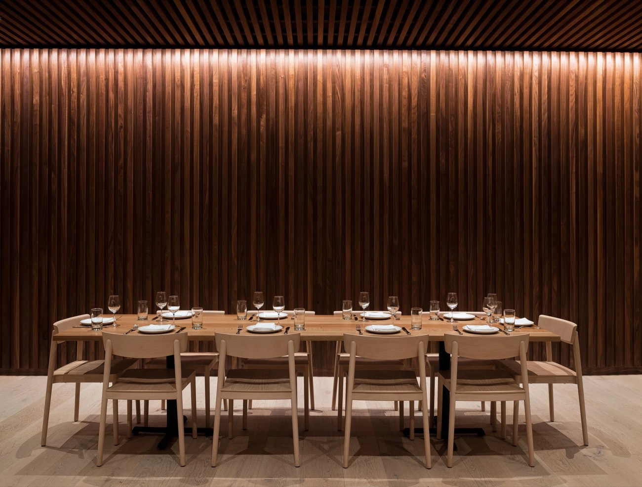 Dining hall with a backlit slatted-wood wall